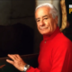 Lazzaro Beligni, detto Giove, in età matura, ritratto in una scuderia con maglione rosso mentre posa accanto al box di un cavallo, in un fotogramma dell’archivio Ricordi di Palio.